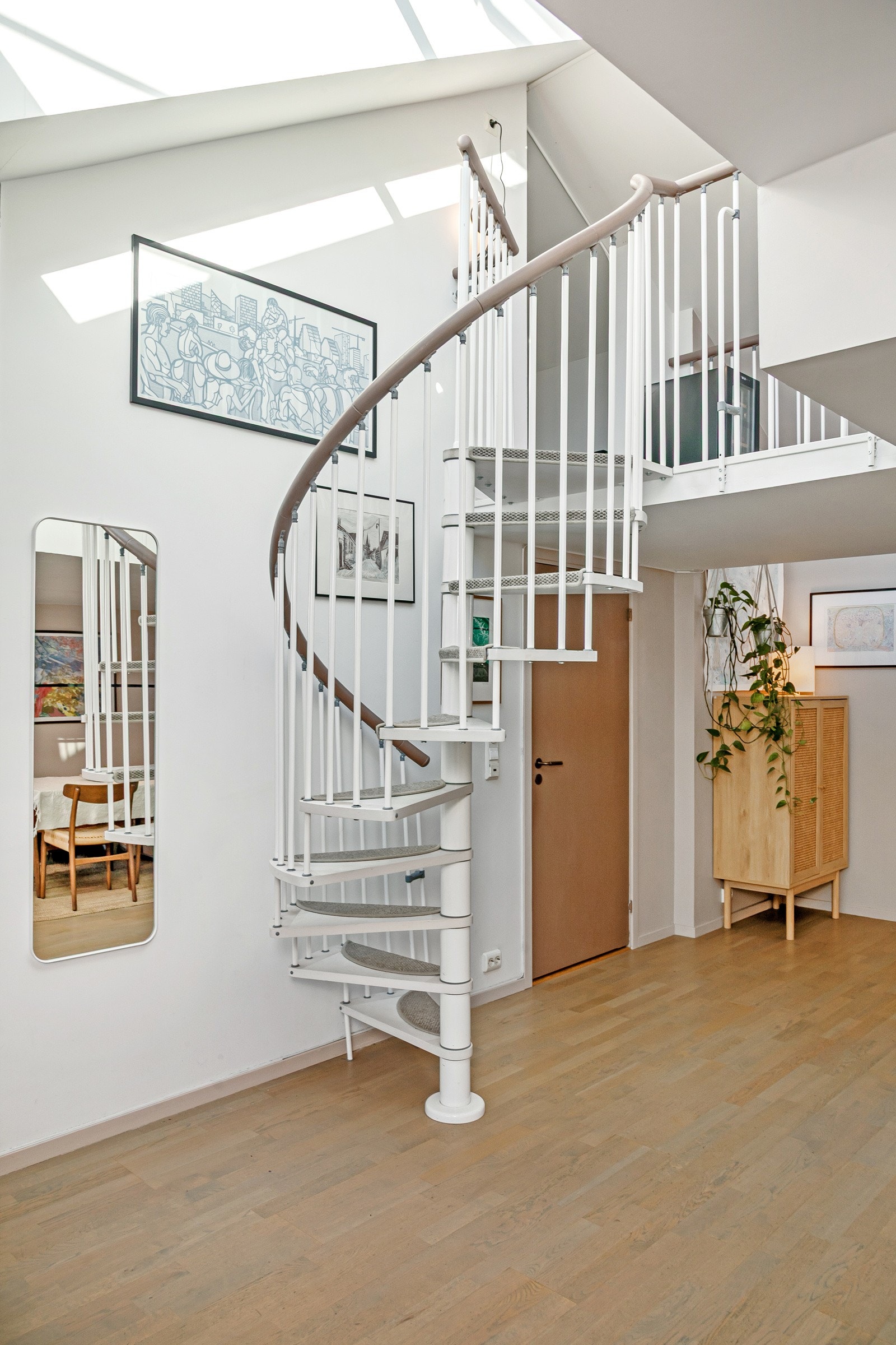 I stuen er det inngang til både soverom og badet, samt en spiraltrapp opp til leilighetens mesanin. Galleribilde