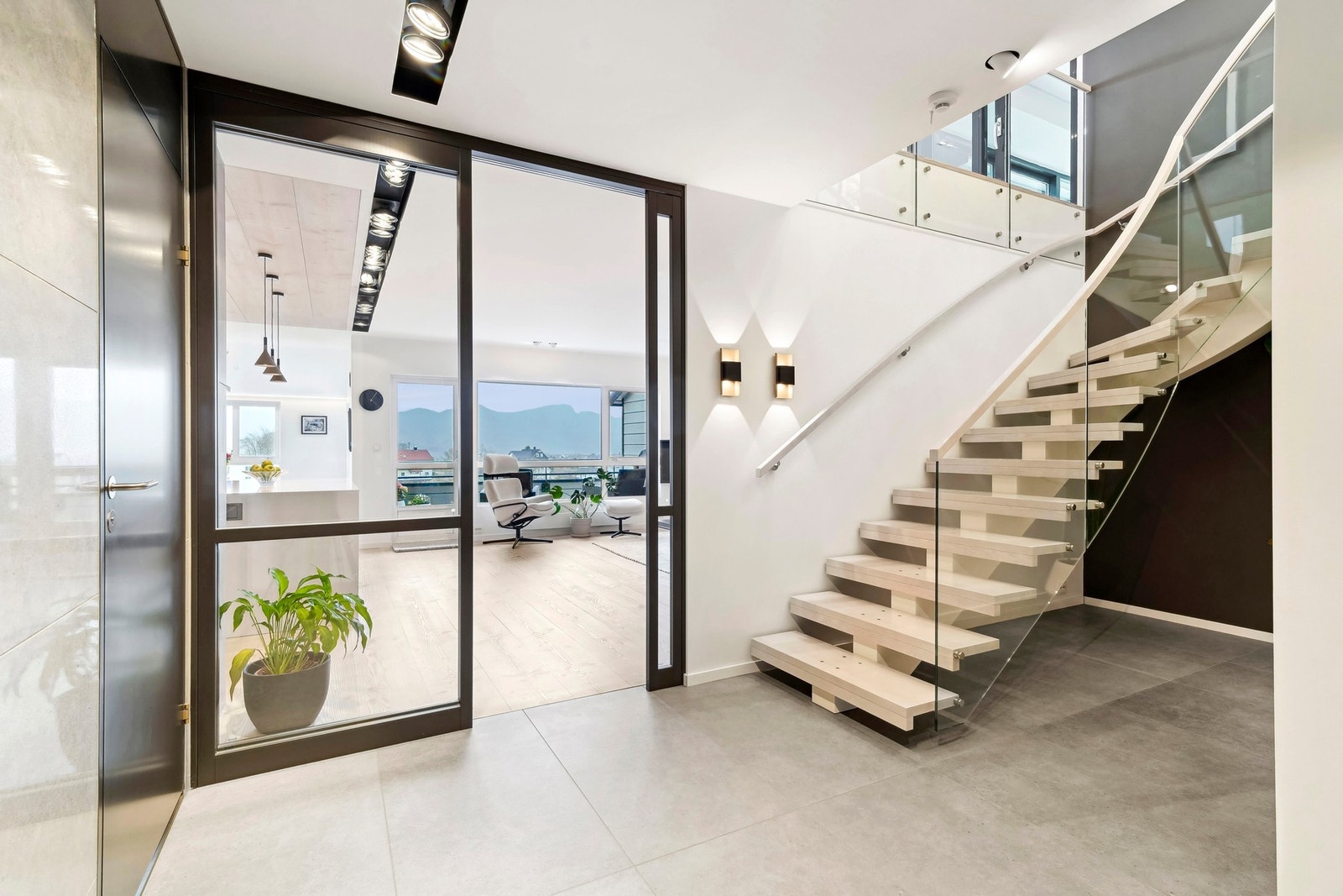 En tofløyet glassdør med sort omramming markerer overgangen til oppholdsrommet og slipper utsikten inn i hallen. Galleribilde