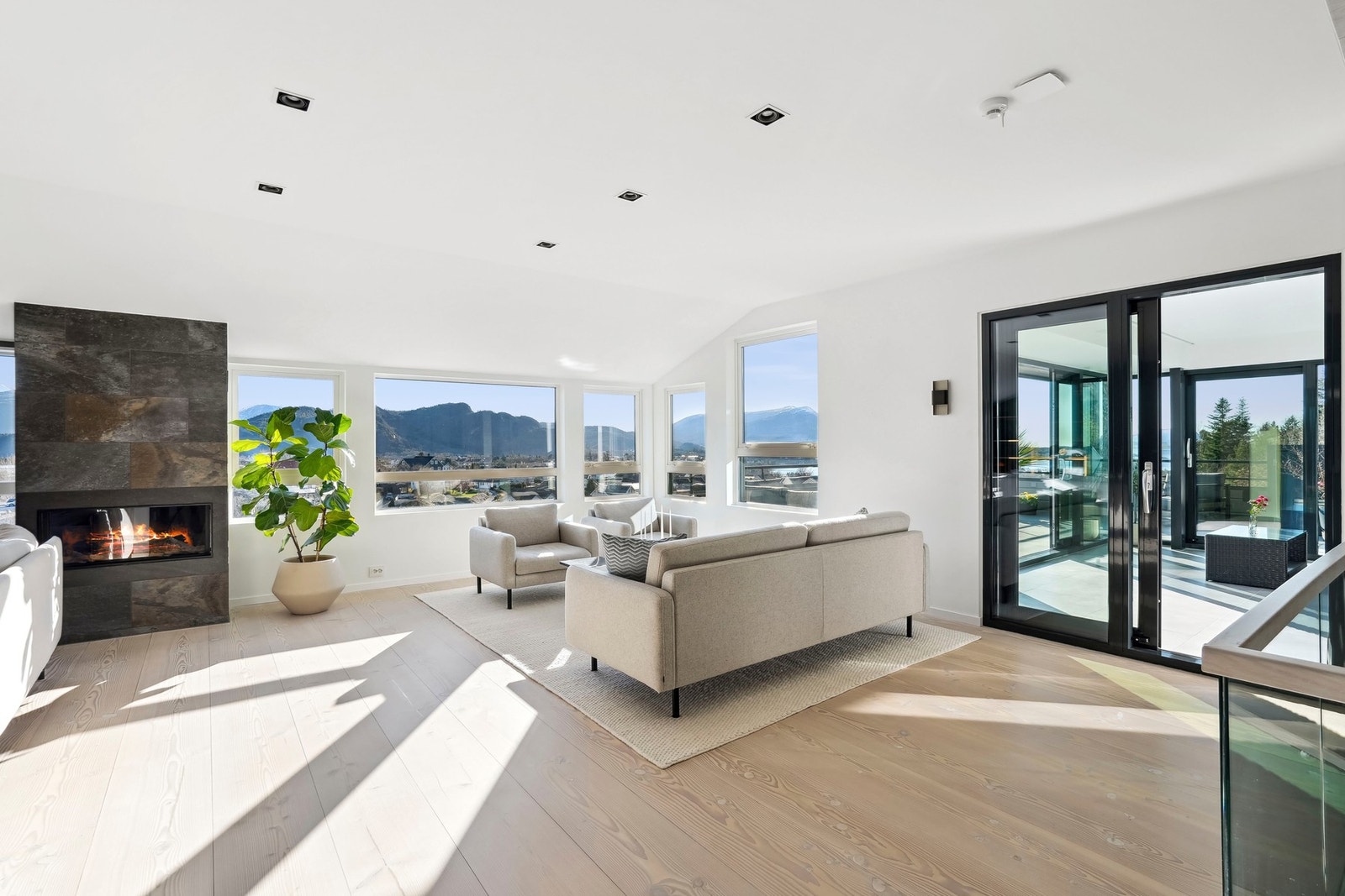 Utsikten er spektakulær og strekker seg til fjord og fjell i to retninger. En lekker gasspeis gir rommet et lunt element og er kledd i mørke, bronsefargede skiferfliser. Galleribilde