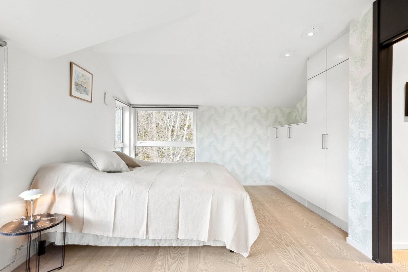 Rommet er innredet med hvite garderobeskap fra HTH, fondvegg i mønstertapet og en skrå himling med downlights. Galleribilde