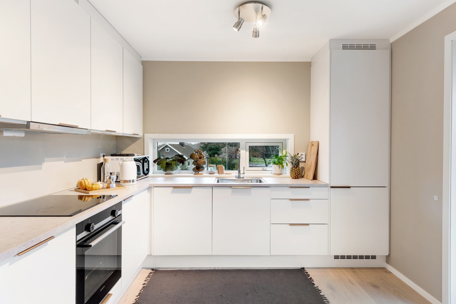 Kjøkkenet har takoppforede skap, hvite, slette fronter og benkeplate i laminat. Galleribilde