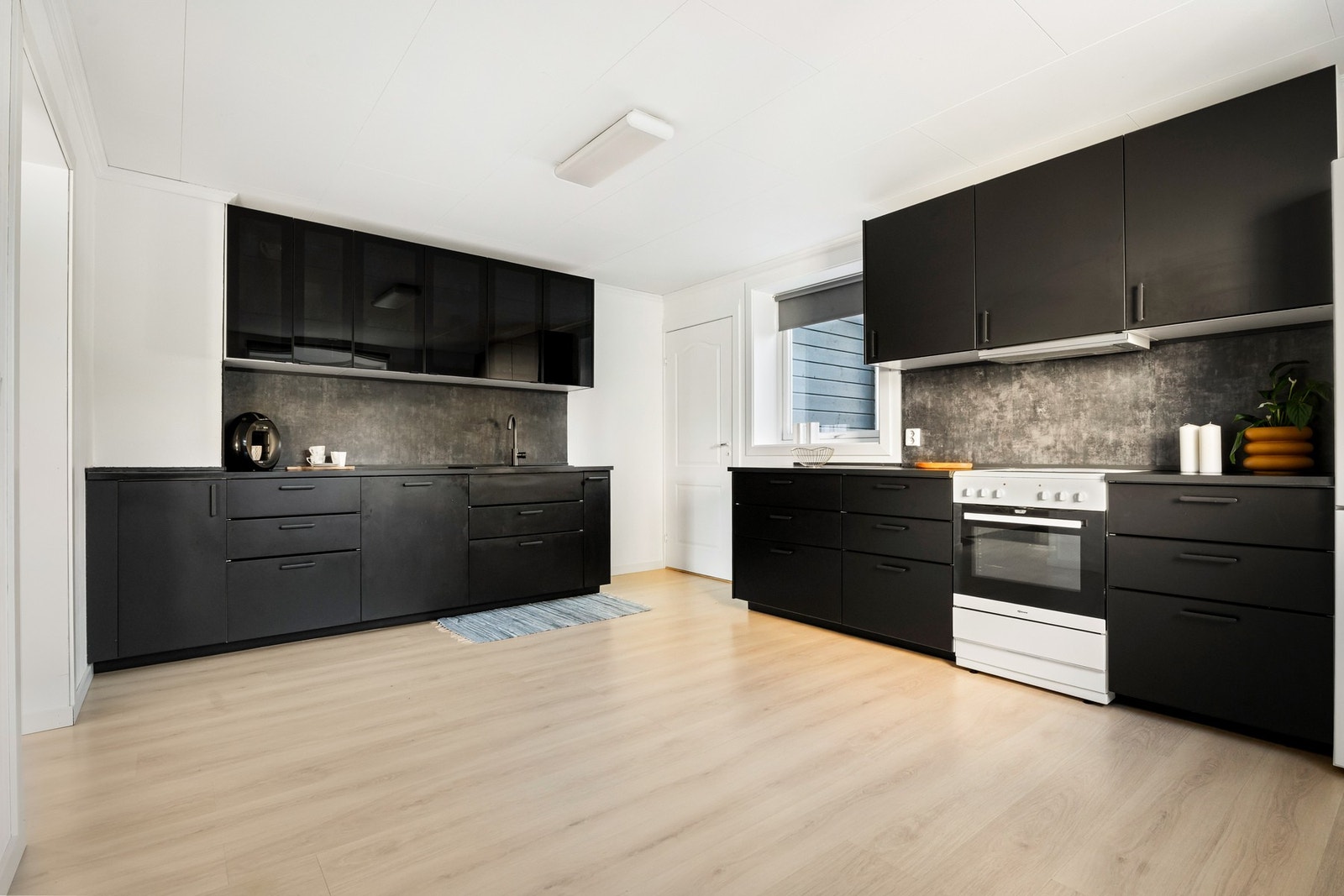 Innredningen har sorte, glatte fronter og matchende laminatbenkeplate med nedfelt sort kum i kompositt. Galleribilde