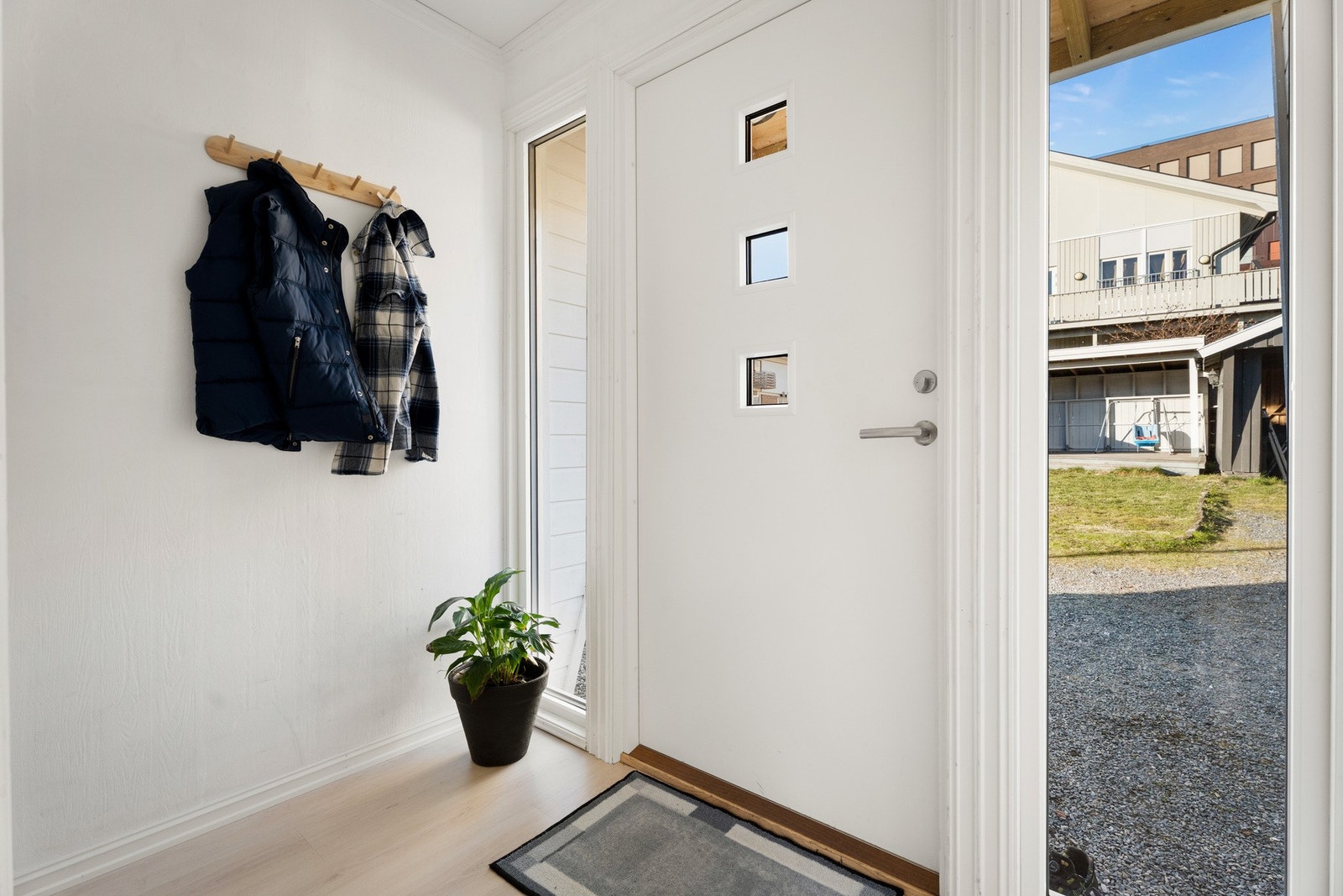 Vel innenfor en ytterdør fra 2022 blir vi ønsket velkommen i en fin entré med hvitmalte vegger og lyst, enstavs laminatgulv. Galleribilde
