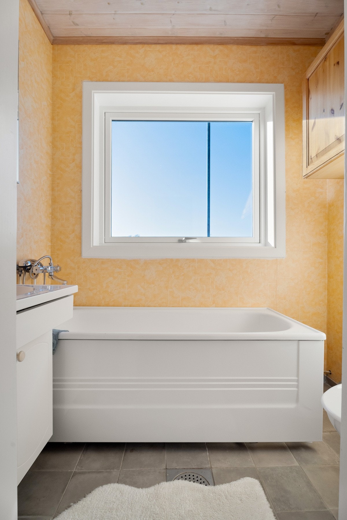 Badet i andre etasje er lyst og pent, med lysegul våtromstapet på veggene og grå fliser på gulv med sluk. Galleribilde