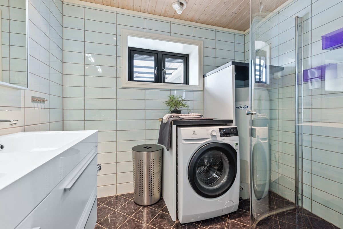 Badet er innredet med baderomsinnredning, dusjvegger, vegghengt toalett og opplegg for vaskemaskin. Galleribilde