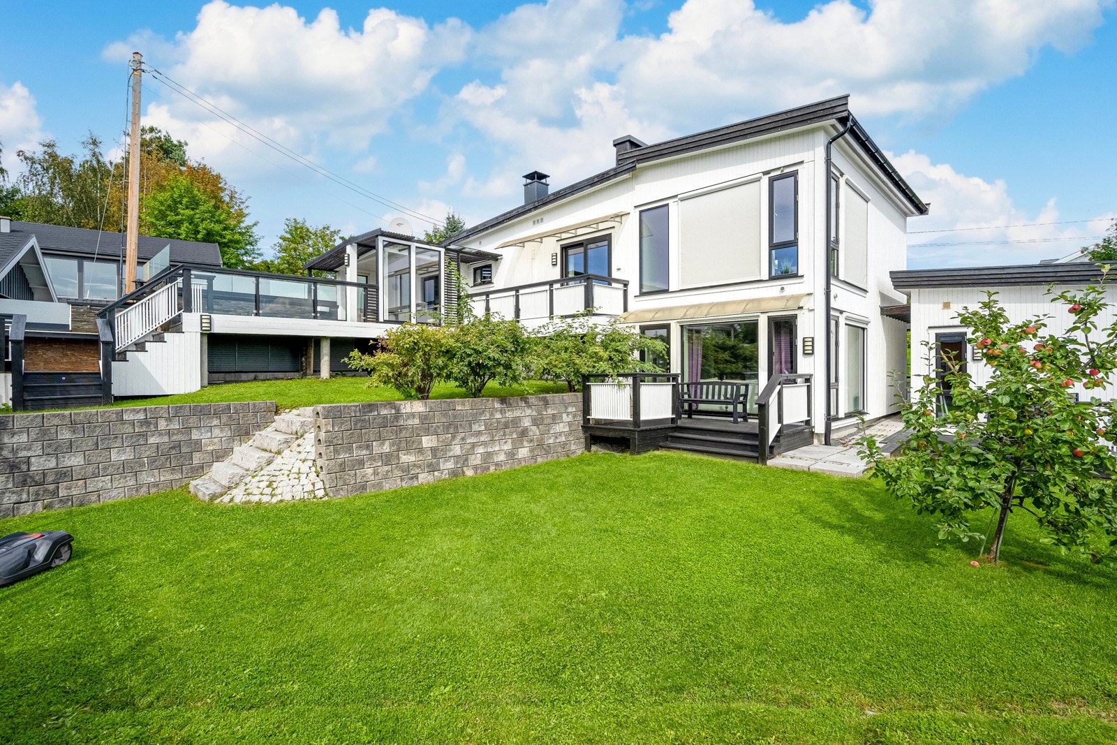 Tomten er nydelig terrassert og pent opparbeidet med støttemurer, brostein, plen og bed, noe som gir et stilfullt inntrykk og er lett å vedlikeholde. Galleribilde