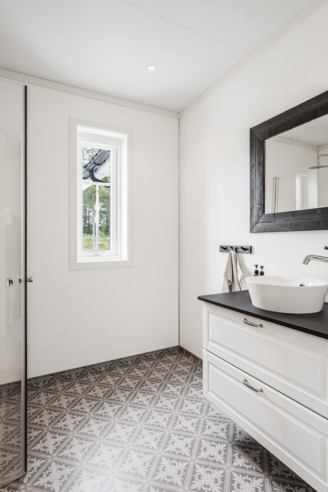Boligen har et bad i hver etasje, og badet i første etasje er innredet med servant på en fin og romslig skuffeinnredning, dusjhjørne med innfellbare glassdører og vegghengt toalett. Galleribilde