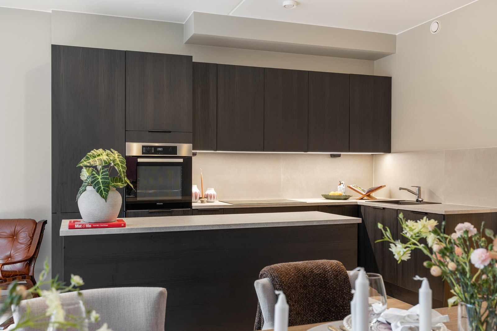 Det er benkebelysning og stikkontakter over kjøkkenbenk, samt fliser mellom benk og overskap Galleribilde