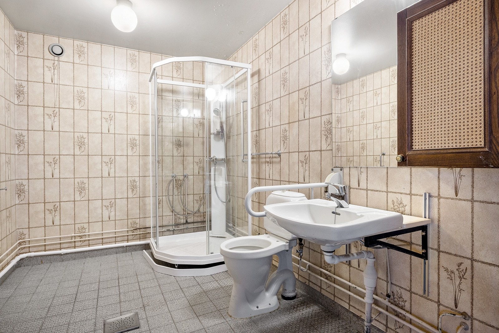 Badet er innredet med dusjkabinett, servant, speil m/overlys, wc, originalt tørkeskap og opplegg for vaskemaskin. Galleribilde