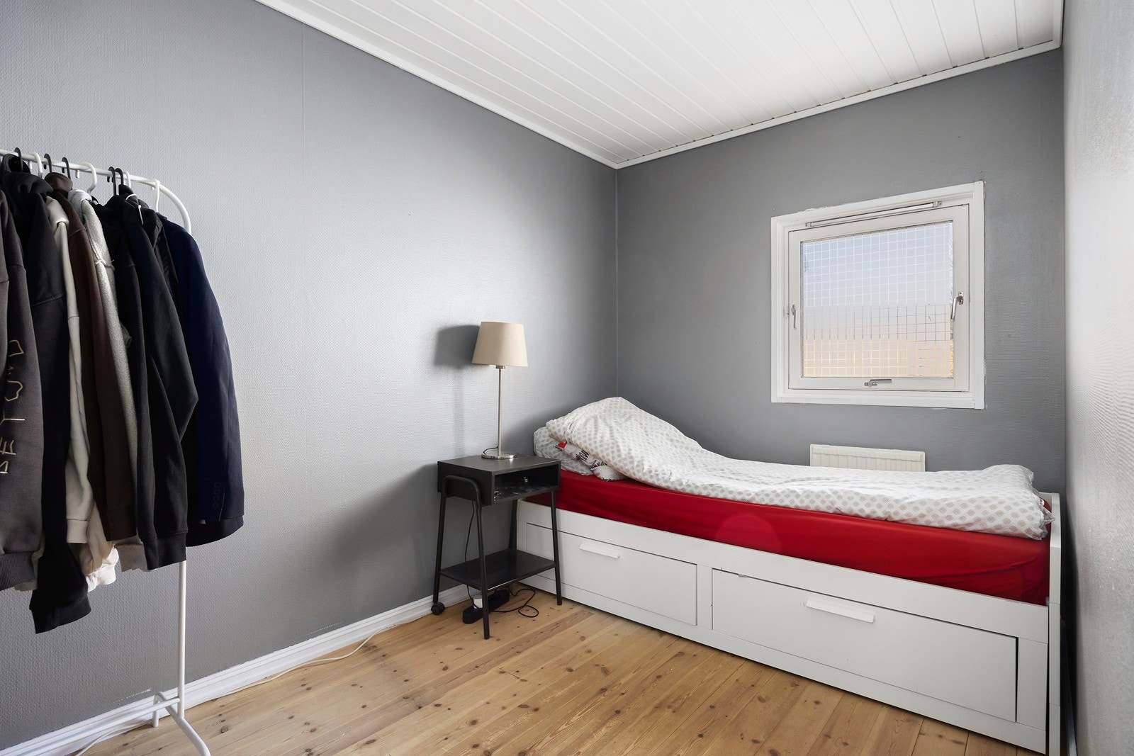Soverommet har grå vegger, lyst tak og tregulv. Galleribilde