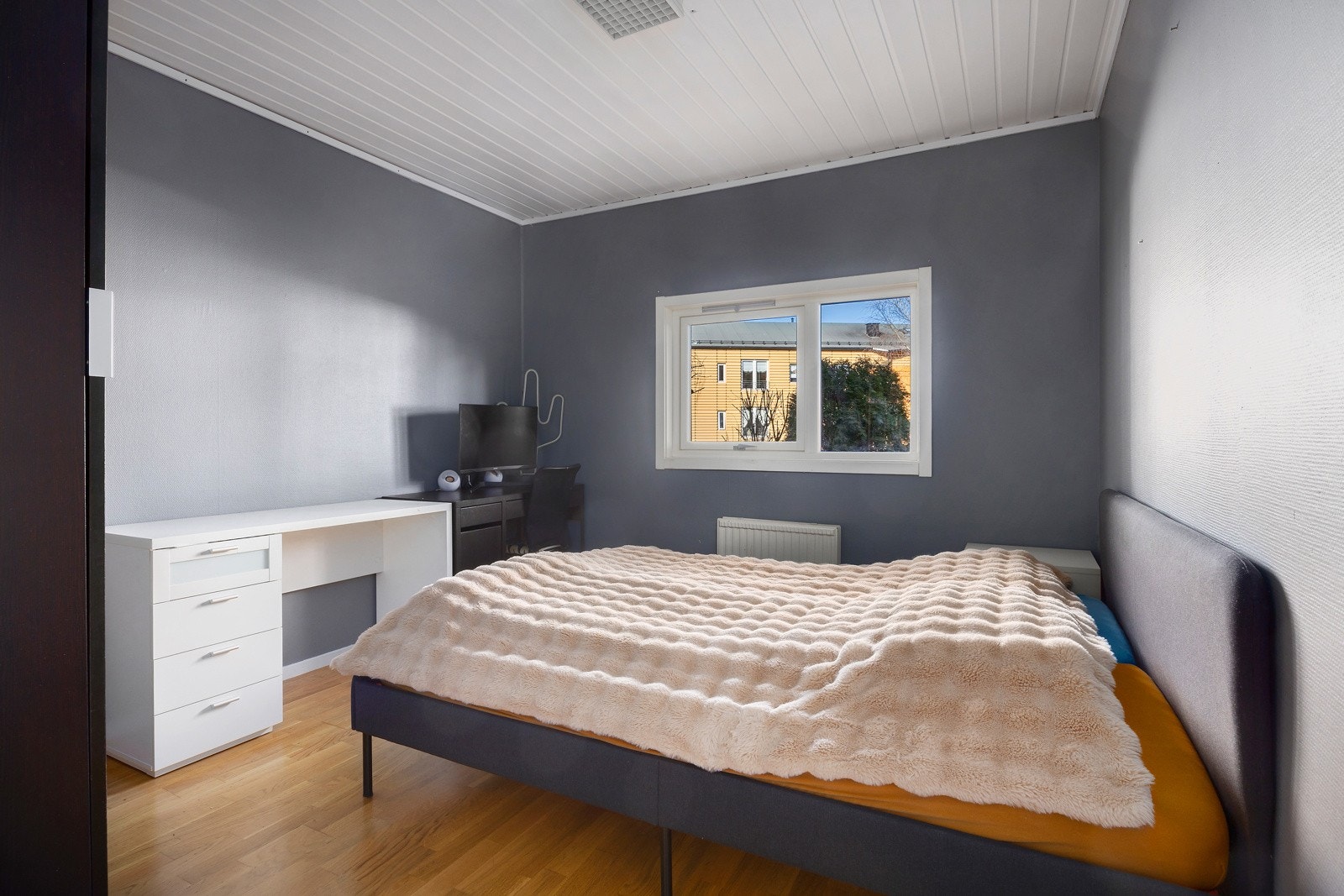 Rommet har grå vegger, hvitt tak, parkettgulv og et vindu som slipper inn naturlig lys. Galleribilde