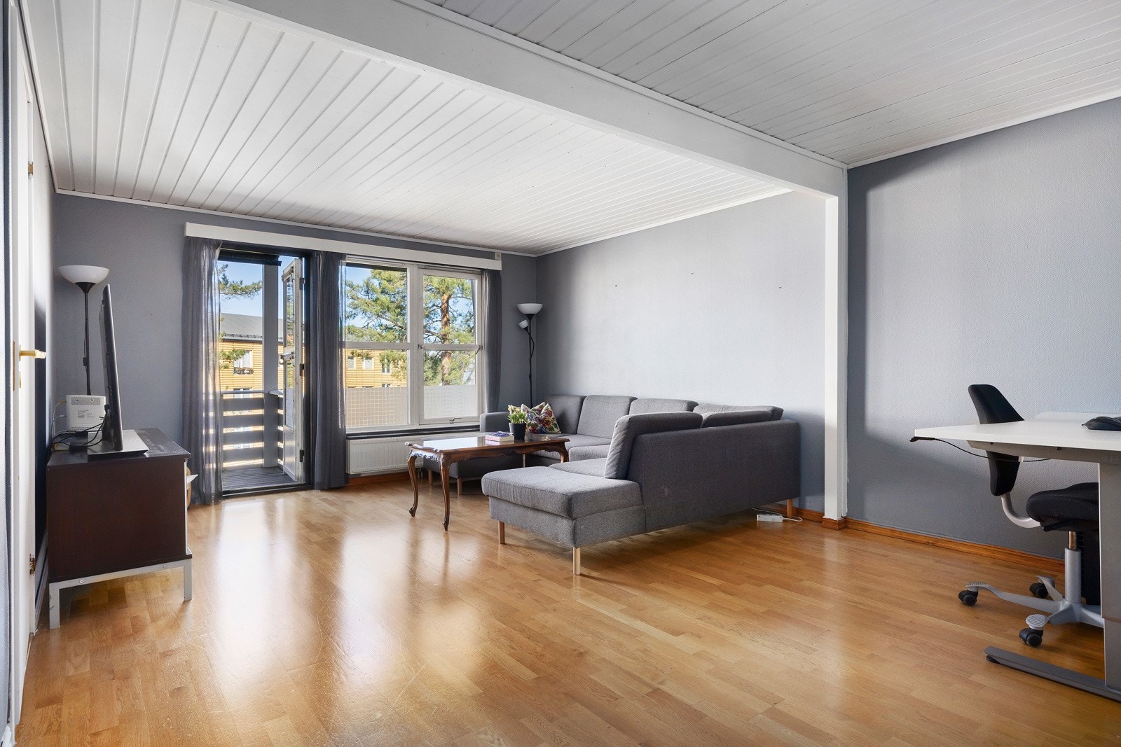 Lyst og romslig stueområde med store vinduer, utgang til balkong og plass til både sofagruppe og spisestue. Galleribilde