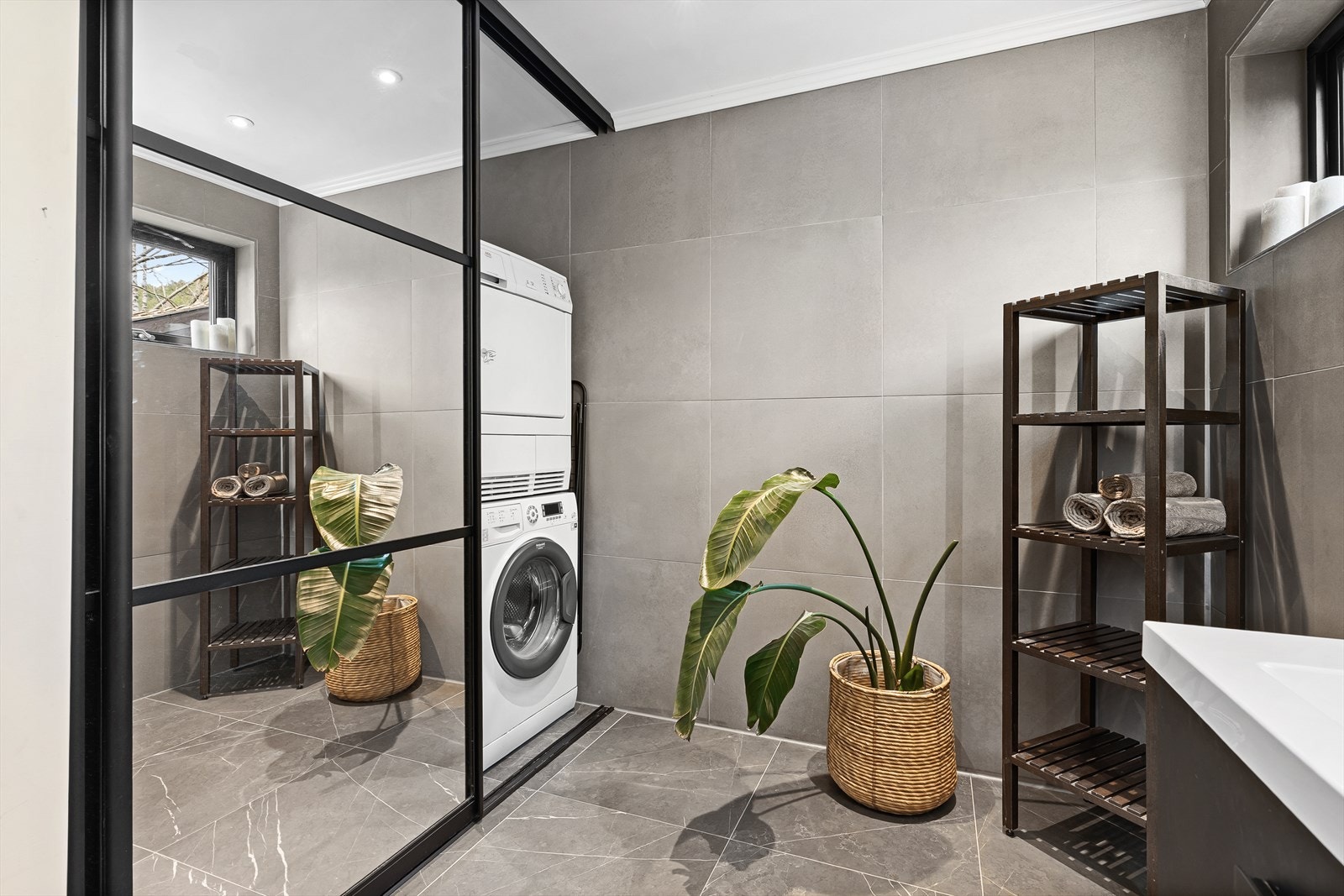 Badet har en smart vaskeromsnisje med skyvedører som skjuler vaskemaskin og tørketrommel når det ikke er i bruk. Forøvrig består badet av et vegghengt toalett, baderomsinnredning med dobbel vask og speil over, samt dusjnisje med regndusj. Galleribilde