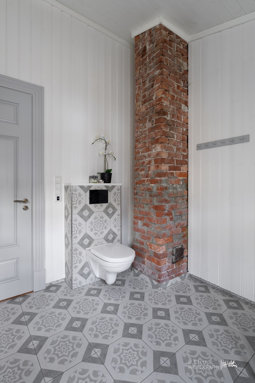 Videre er et vegghengt toalett montert. Elektriske varmekabler er installert i gulvet. Badet ventileres via en elektrisk avtrekksvifte i veggen og en tilluftspalte under dørbladet. Galleribilde