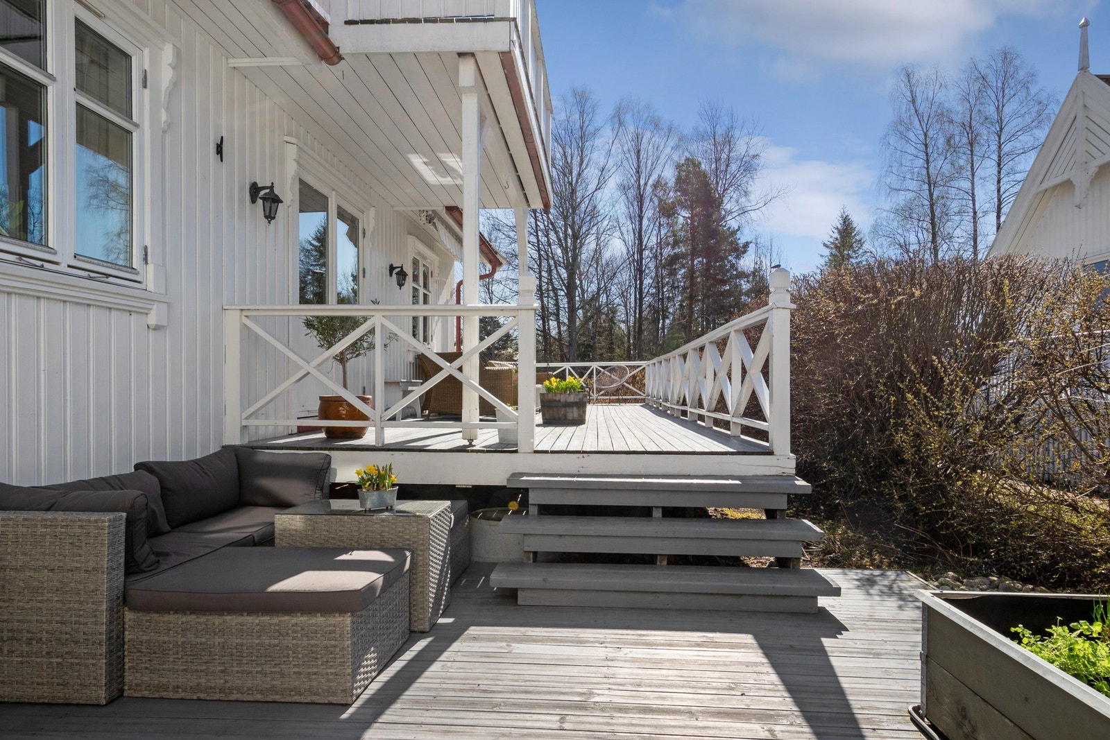 Terrassen har gråbeiset tredekke og hvitmalt rekkverk. Galleribilde