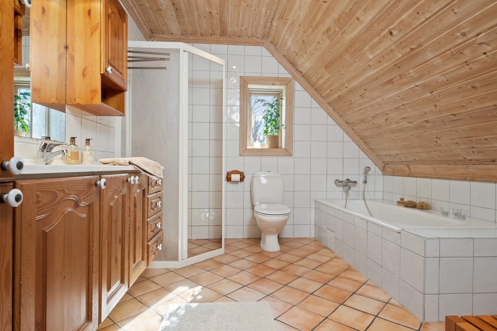 Badet ligger ved soverommene i andre etasje, og har hvite fliser på veggene og terracottafargede fliser på gulv med gulvvarme. Galleribilde