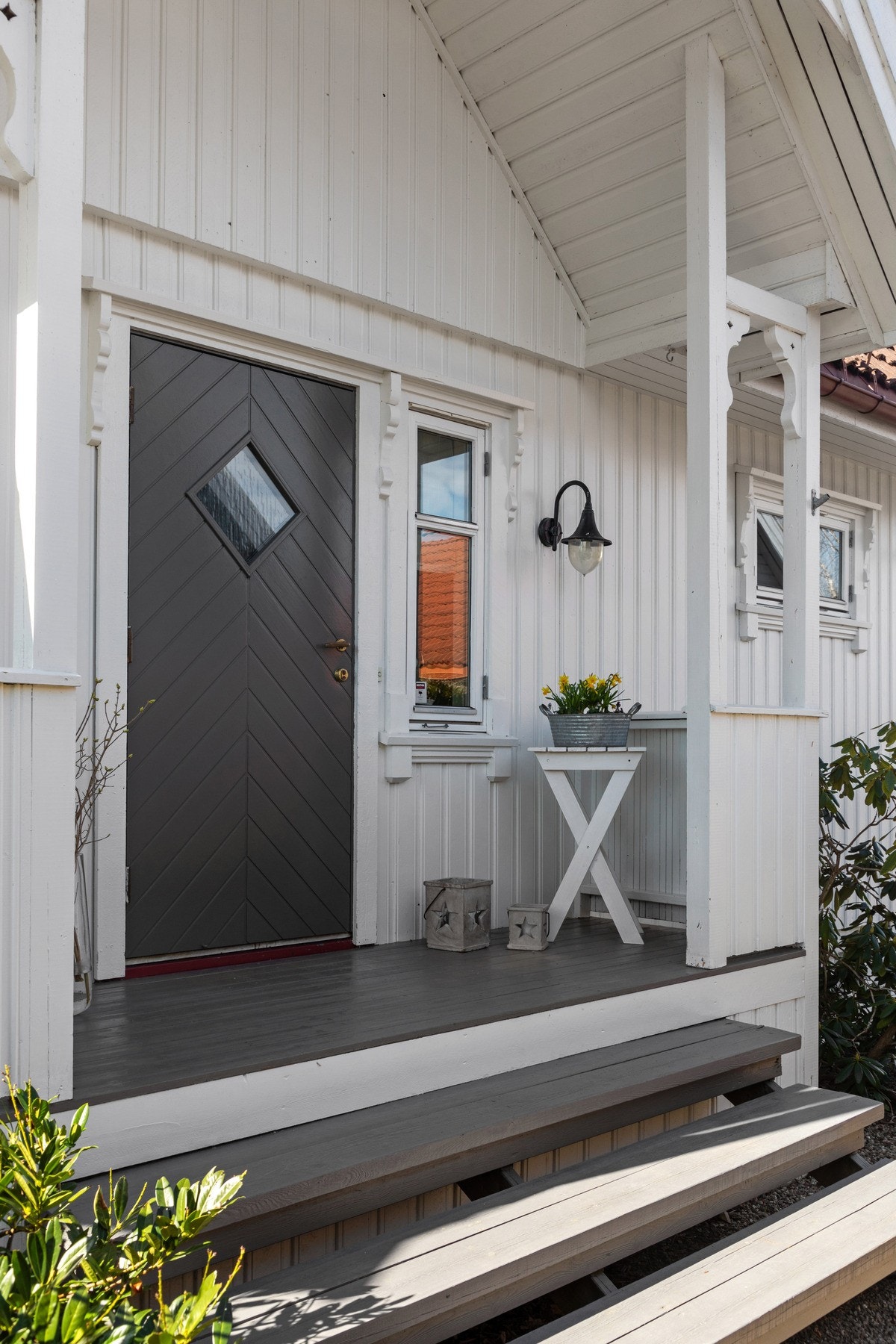 Eneboligen har et pent, overbygd inngangsparti med gruslagt adkomst, bred tretrapp og veggmontert utebelysning. Galleribilde