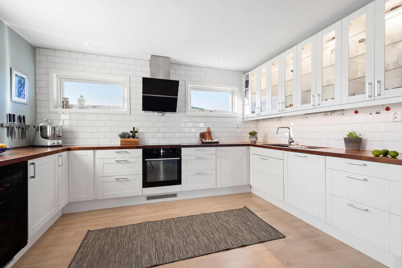 Innredning fra 2019 med hvite, profilerte fronter, benkeplater av heltre og nedfelt oppvaskkum med ett-greps armatur. Galleribilde