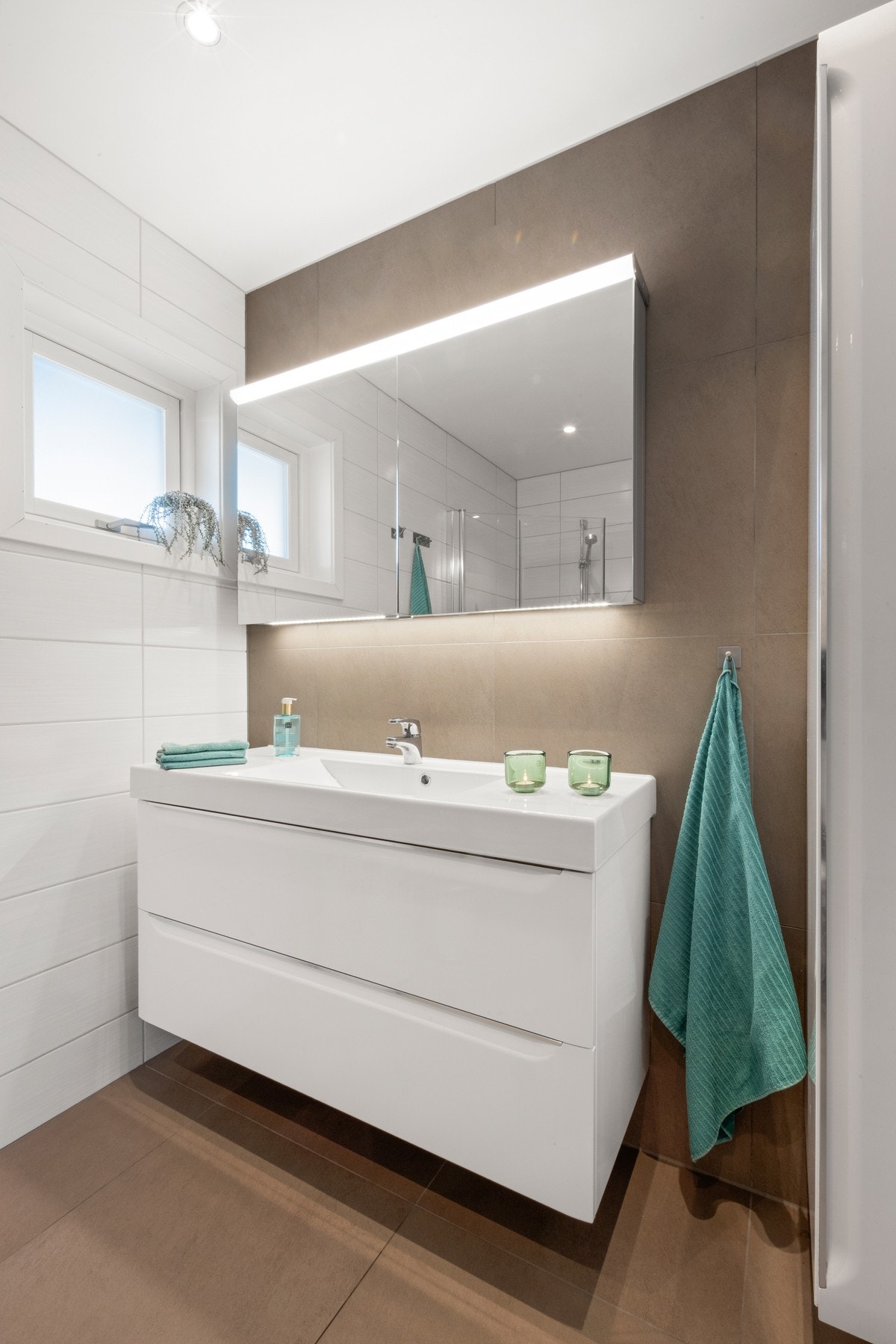 Badet er innredet med servant med underskap og speilskap, dusjnisje med innfellbare glassdører i herdet glass, samt vegghengt toalett. Galleribilde