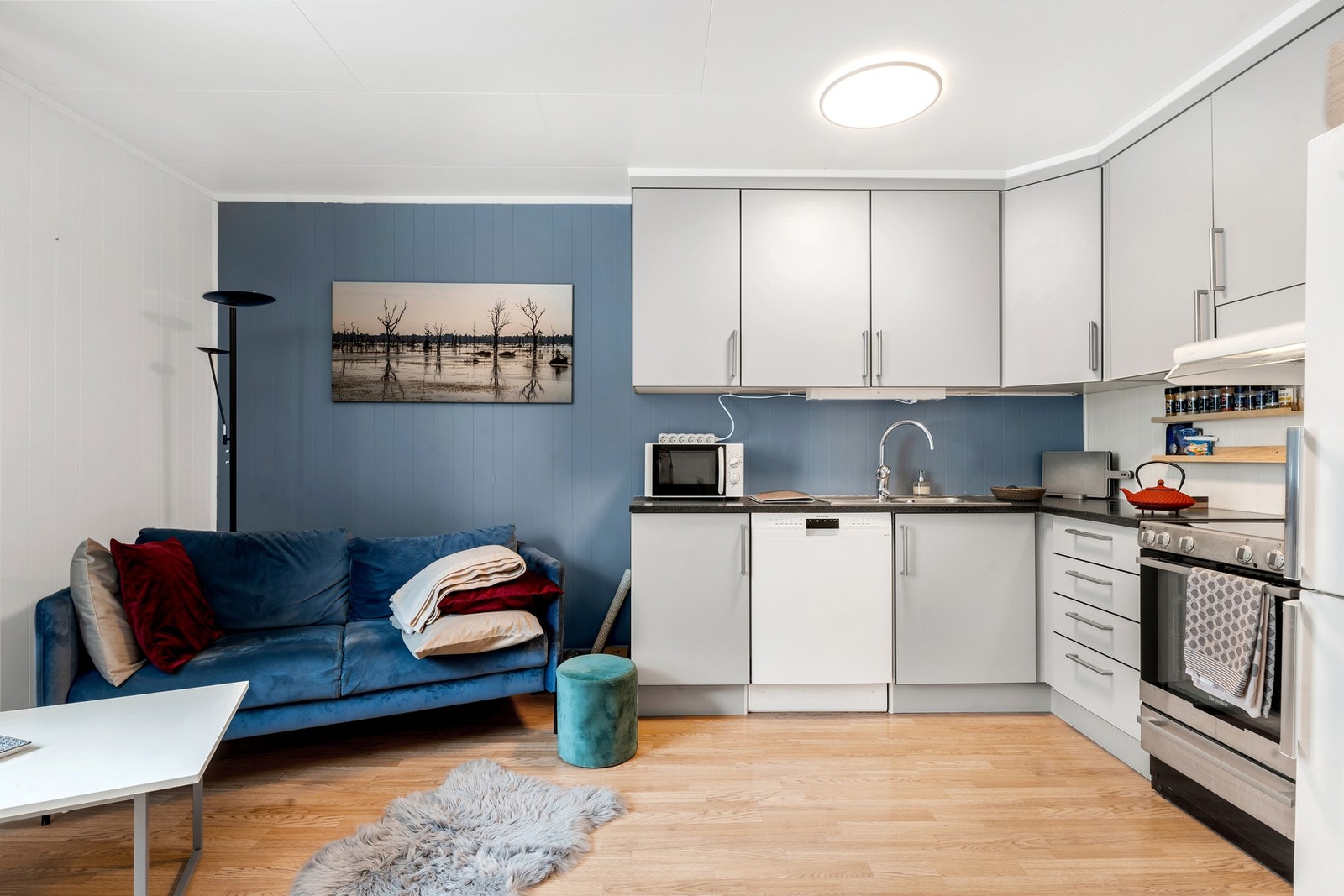 Åpen og sosial løsning mellom stue og kjøkken. Kjøkkenet er innredet med glattefronter, benkeplate i laminat, frittstående komfyr og kjøleskap med fryser, og oppvaskmaskin under kjøkkenbenk. Galleribilde