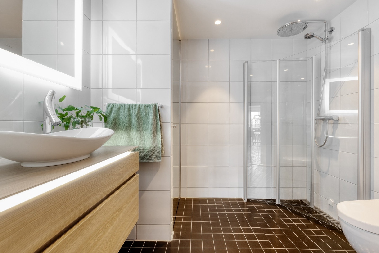 I denne leiligheten er det to delikate bad. Dette badet ligger i tilknytning til entreen. Her er det tidløst innredet med lyse fliser på vegger, samt downlightsbelysning i himlingen. Galleribilde