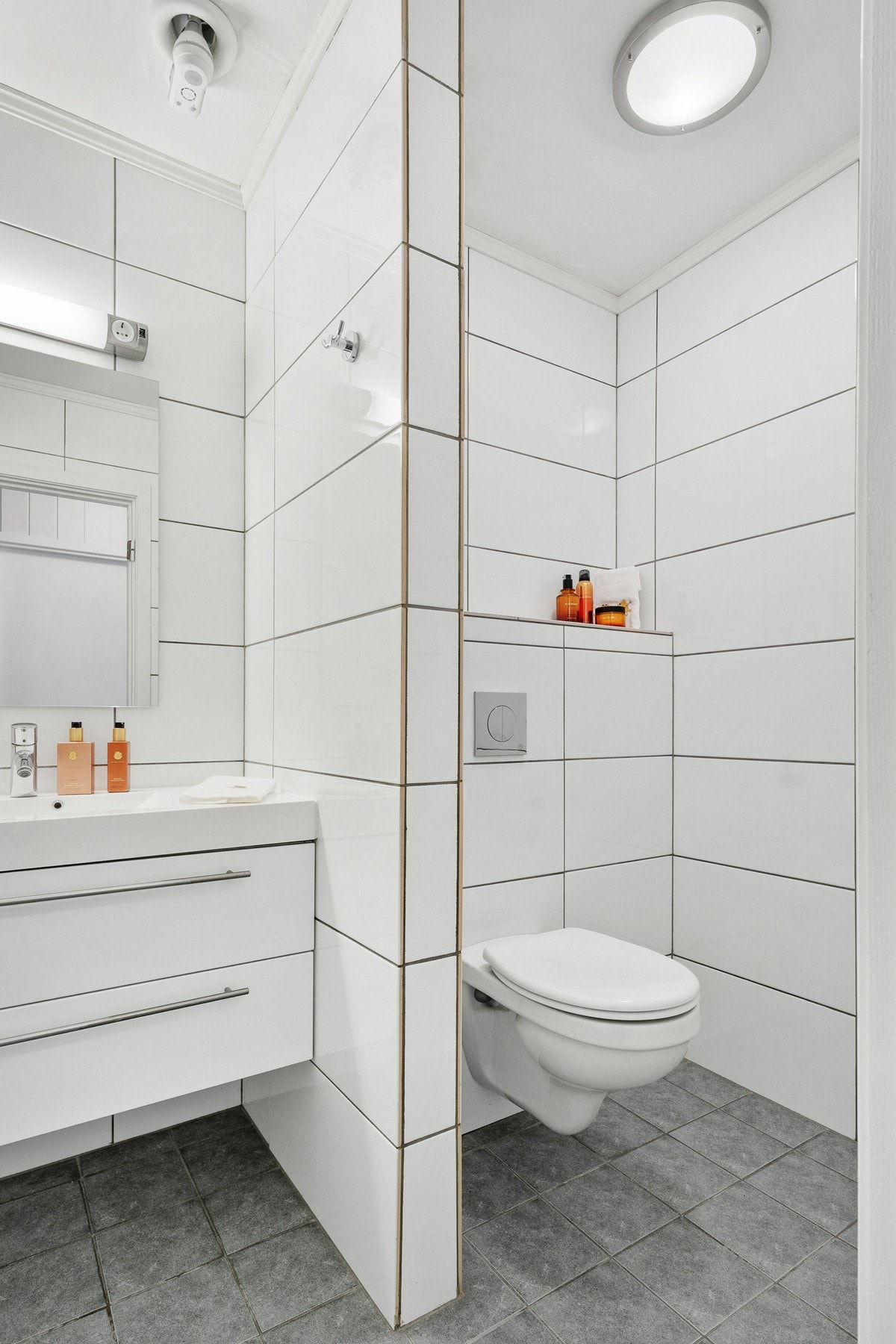 Badet er praktisk innredning med nedfelt servant, vegghengt toalett og dusj med dusjvegger. Galleribilde