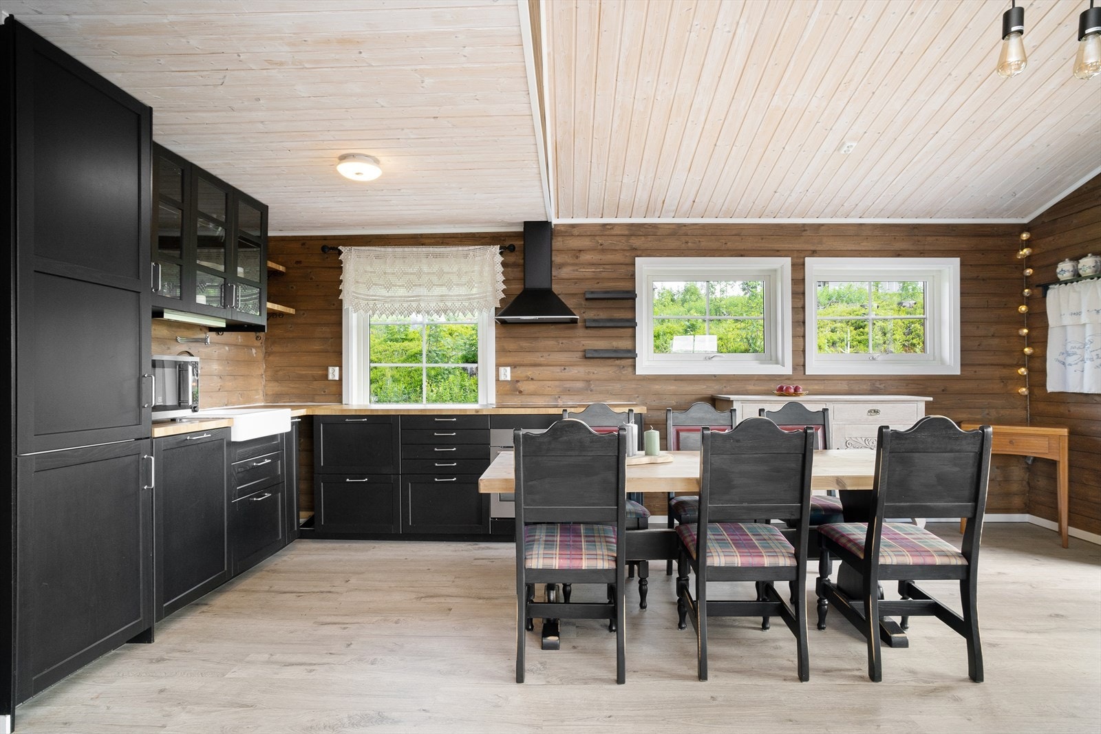 Et mørkt og moderne hyttekjøkken med heltre benkeplate og god lagringsplass i skuffer og skap. Hvitevarene er integrerte. Galleribilde