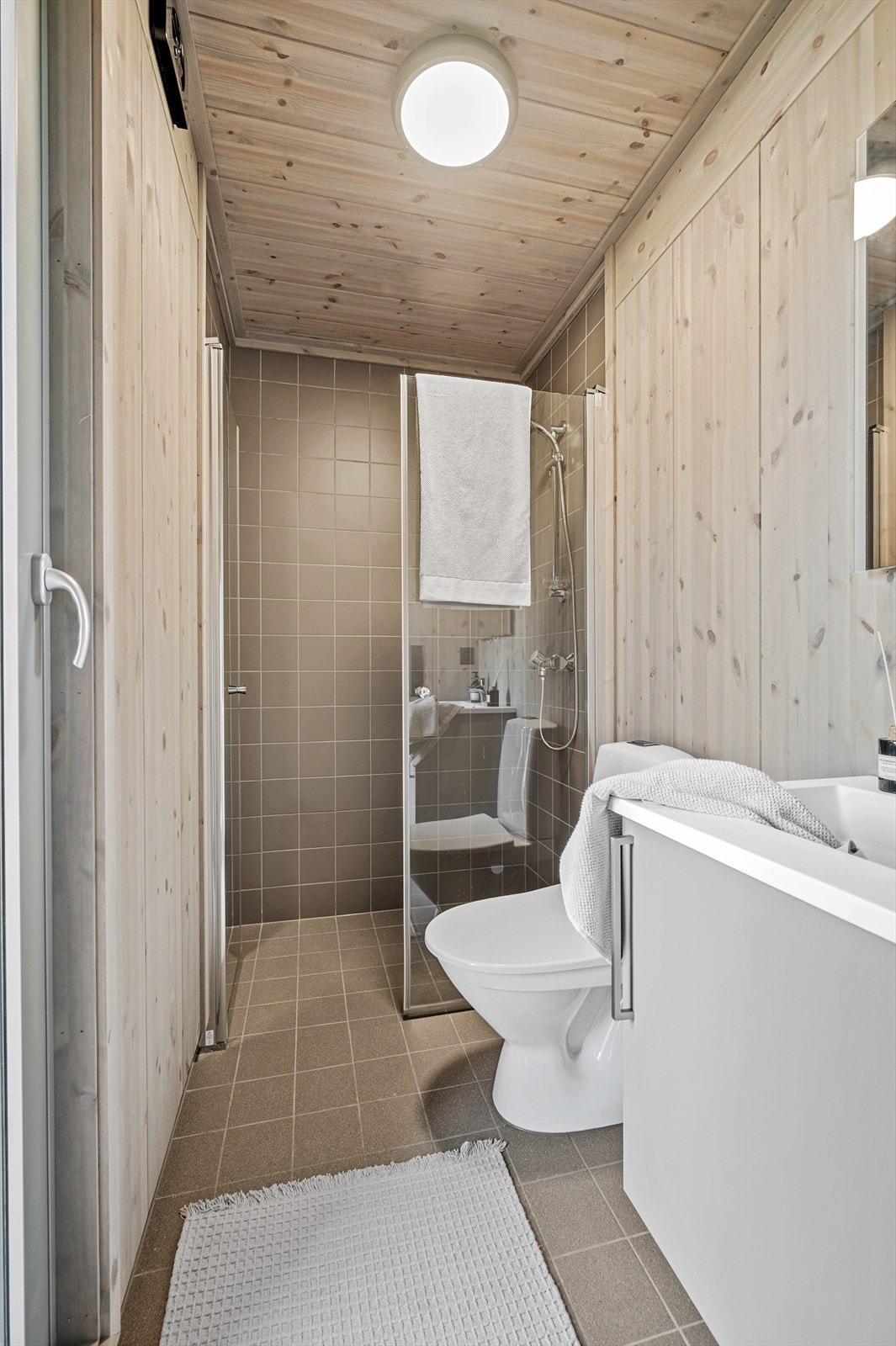 Både gang og bad har flislagt gulv med varmekabler. Badet inneholder wc, dusjhjørne og servant med underskap. Galleribilde