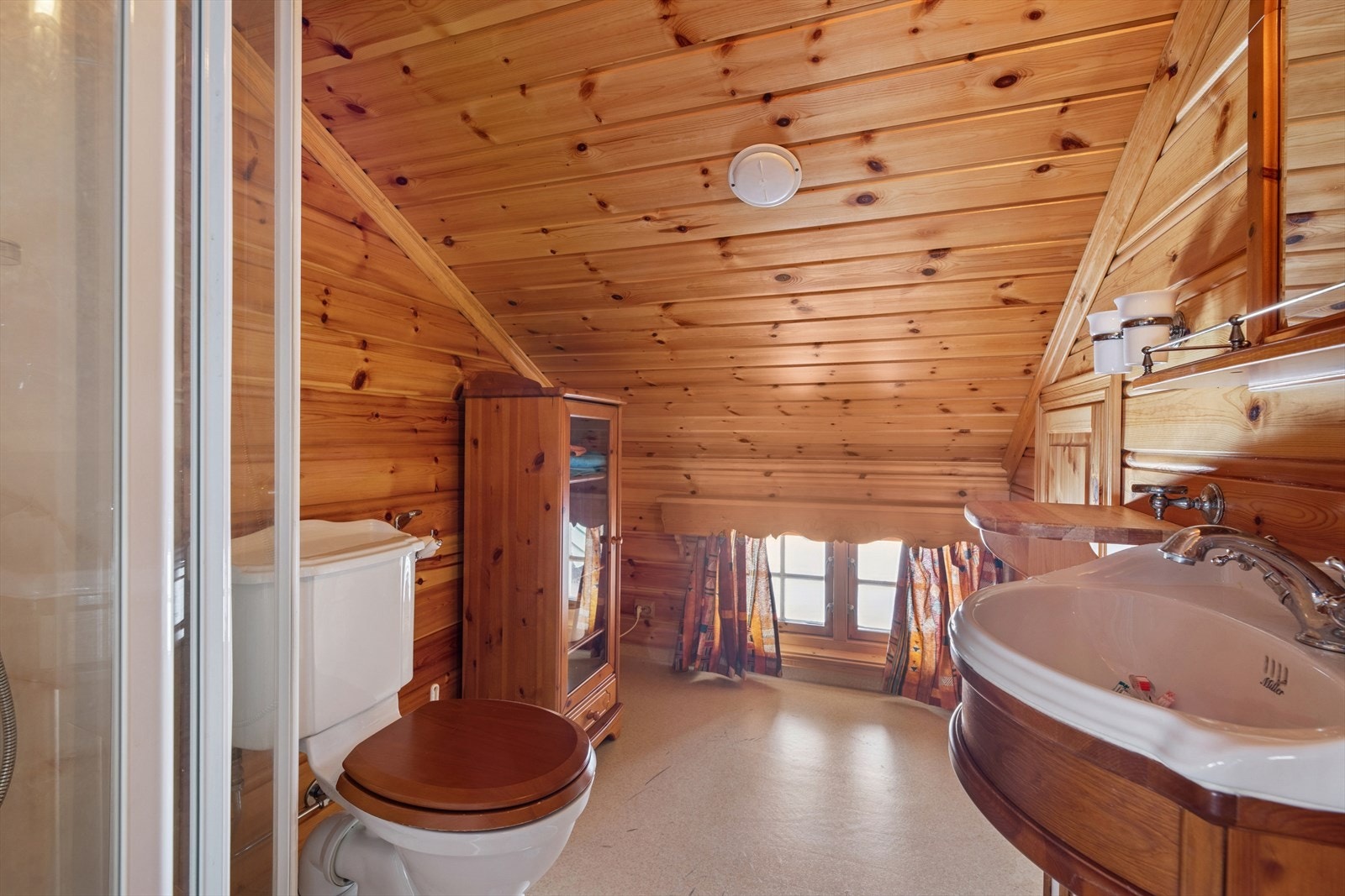 Badet på loftet har panel/tømmer og våtromstapet/belegg på veggene. Badet er utstyrt med nedfelt servant, toalett og dusjkabinett. Galleribilde