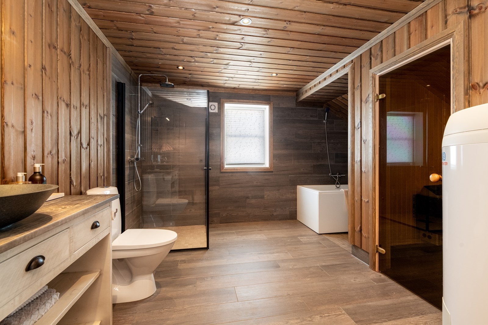 Stort og lekkert baderom innredet med toalett, servantmøbel, dusjhjørne og badekar, samt badstue. Galleribilde