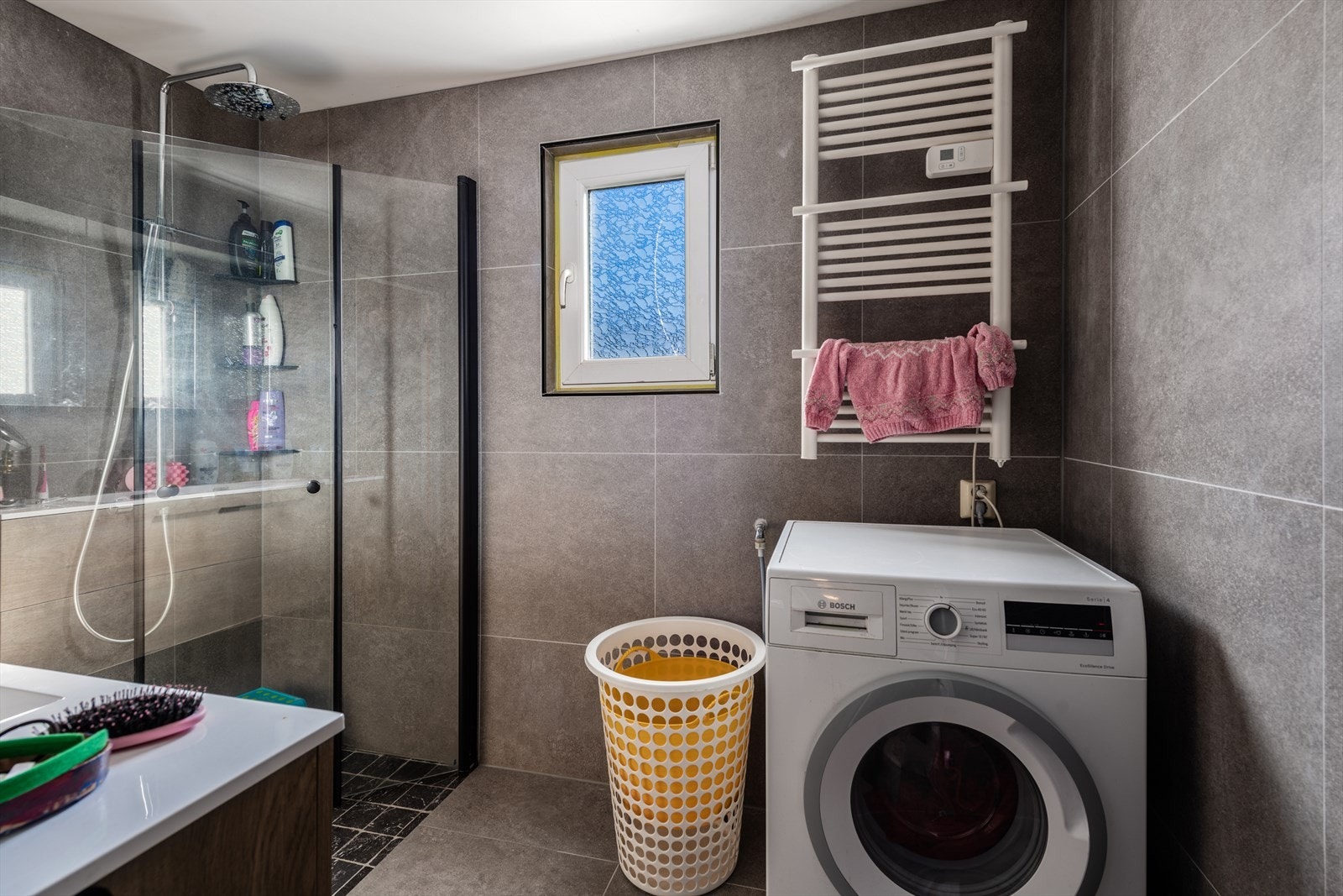 Flislagte overflater og varme i gulv. Innredning med servant og dusjvegger i glass, samt opplegg for vaskemaskin. Galleribilde