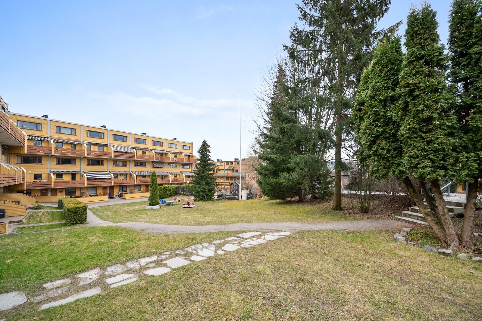 Fellesarealet er pent opparbeidet med asfalterte veier, gressplen og lekeapparater. Galleribilde