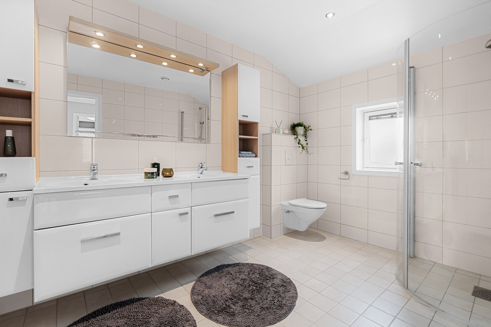 I tilknytning til de tre gode soveromene i 2.etg. er det også et stort og godt bad med gulvvarme og innfelt downlights. Badet er innredet med vegghengt klosett, dobbel servant nedfelt i innredning, speil med lys og dusjhjørne med svingbare glassdører. Galleribilde