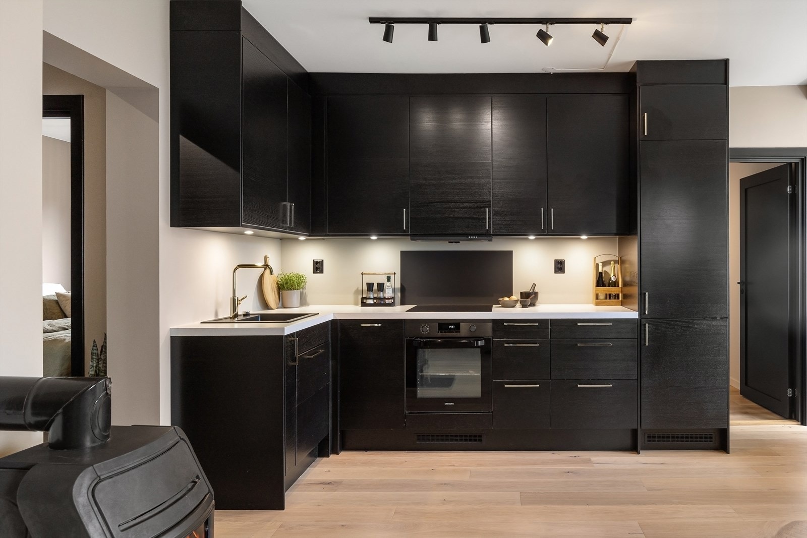 Benke- og overskap med slette fronter og benkeplate i laminat, komfyrvakt over platetopp og waterguard under vask. Integrert ovn, kjøle/fryseskap, ventilator, platetopp og oppvaskmaskin. Galleribilde