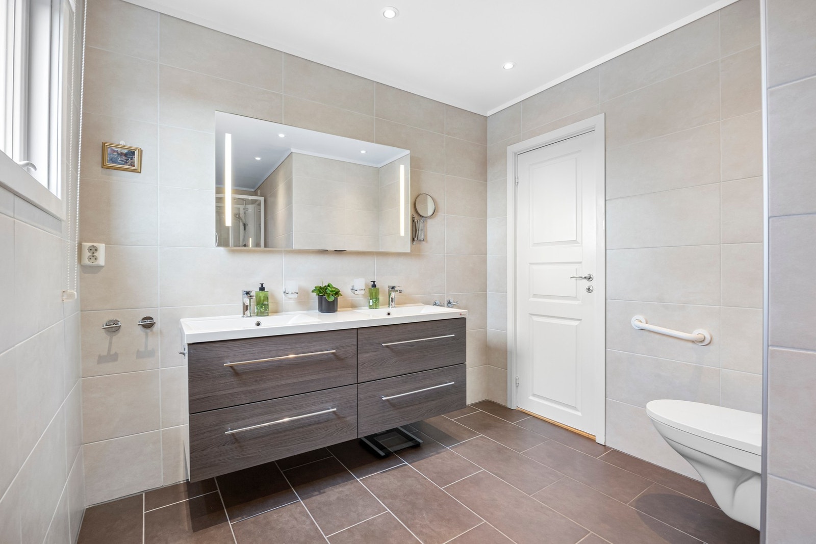 Pent bad fra 2013 med flislagt gulv og vegger, dobbel servant med god skuffeplass, dusj, vegghengt toalett og bidé Galleribilde