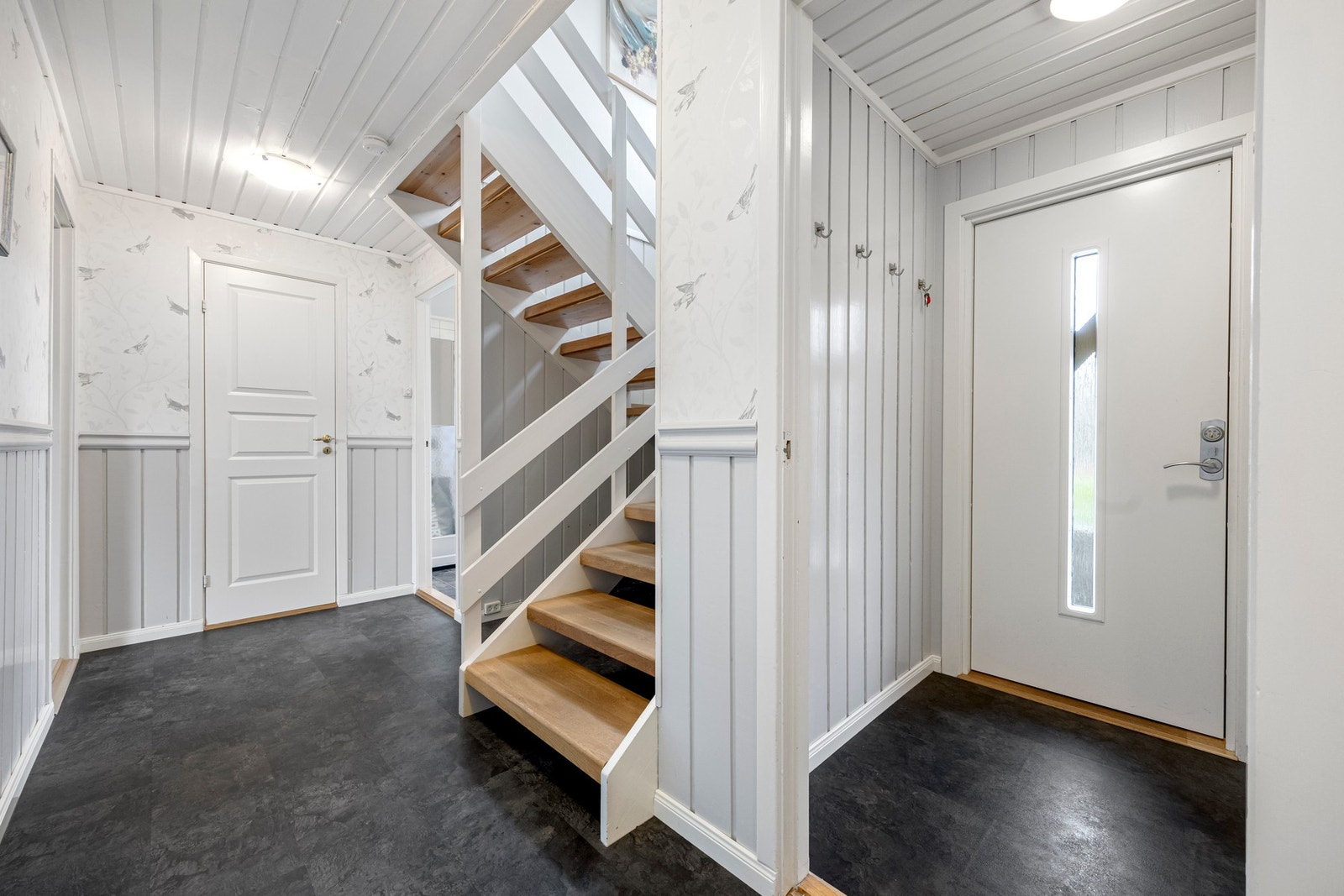 Velkommen inn! I vindfanget er det plass til sko og yttertøy, mens det er et integrert garderobeskap i gangen. Her er det også en vedovn som gir god grunnvarme Galleribilde