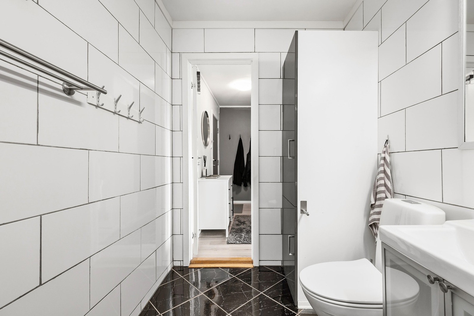 Baderomsinnredningen består av servant på underskap, speil med belysning og overskap med speil. Videre er det toalett og dusjkabinett. Galleribilde