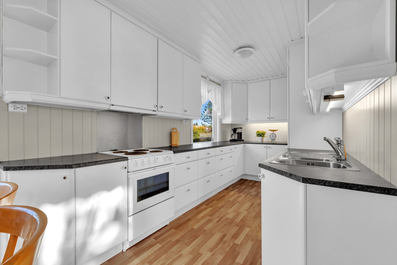 Lys kjøkkeninnredning fra 2009 med hvite glatte fronter og laminert benkeplate med nedfelt oppvaskkum av rustfritt stål med ett-greps armatur. Galleribilde