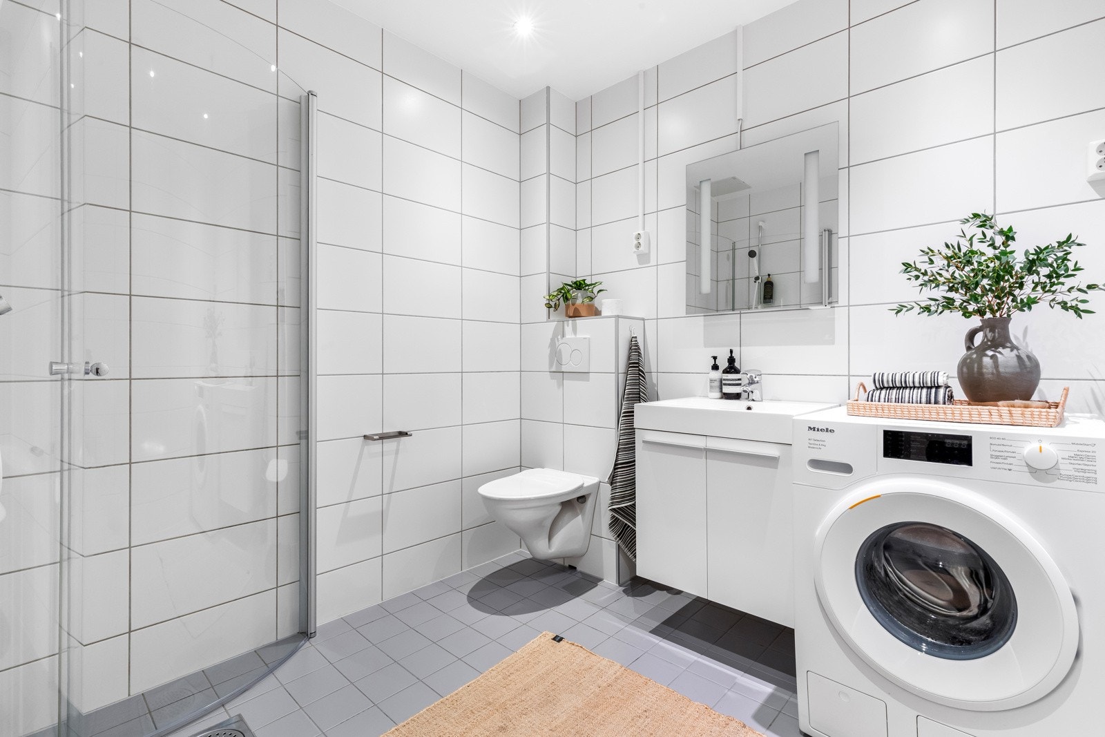 Moderne baderom i lys utførelse med dusjnisje, opplegg for vaskemaskin og vegghengt WC Galleribilde