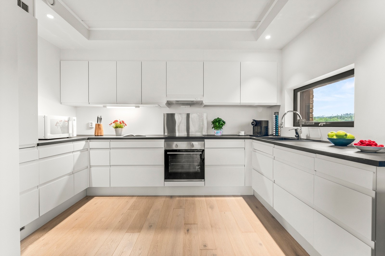 Innredningen har laminterte, glatte fronter, benkeplate av laminat, metallplate bak platetoppen og belysning under overskapene. Hvitevarene er integrerte og består av kjøleskap med frysedel, komfyr, platetopp med induksjonsfunksjon og oppvaskmaskin Galleribilde