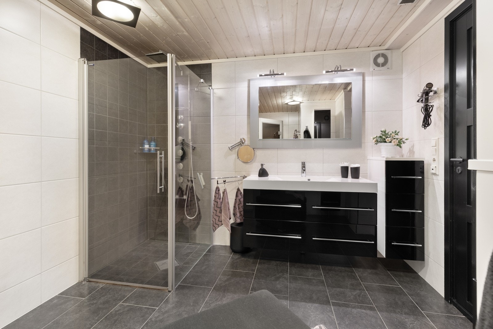 Badet har hvite fliser på veggene og koksgrå fliser på gulv med gulvvarme. Galleribilde