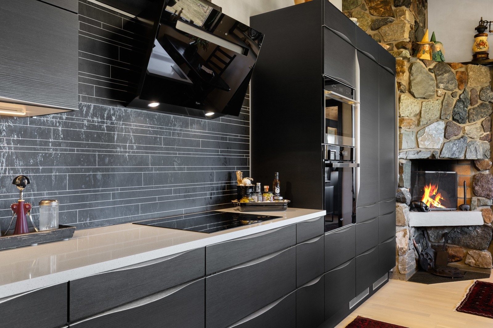 Veggene over benken er kledd med sorte plater i flisimitasjon, og under overskapene er det montert god arbeidsbelysning. Galleribilde