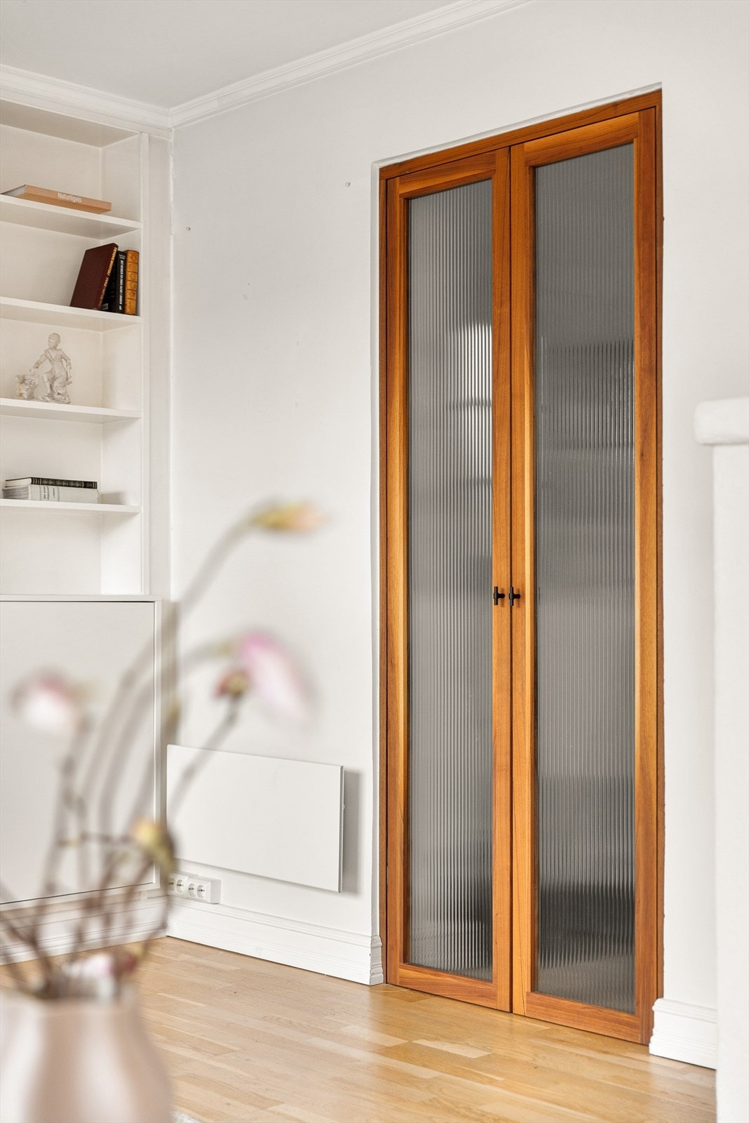 Dobbel dør med rillet glass og ramme i mørklakket Valnøtt mellom entré og stue ble tegnet av interiørarkitekt Cecilie Claussen og laget av møbelsnekker James Bagshaw i 2020. Galleribilde