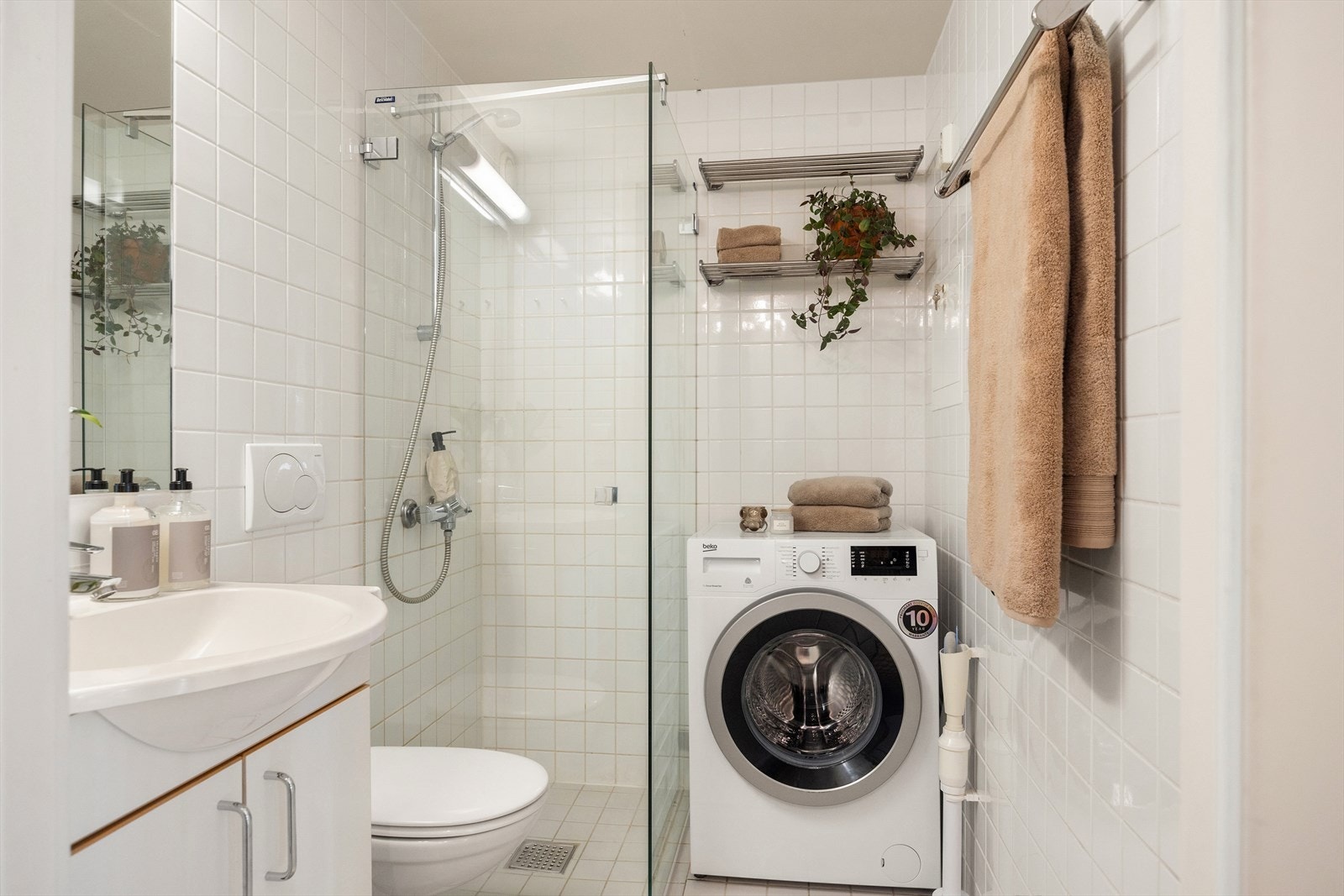 Pent og moderne baderom med varme i gulv og opplegg for vaskemaskin. Galleribilde