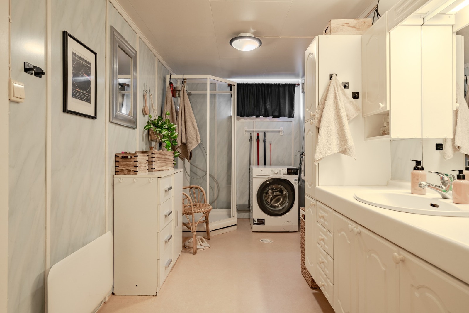 Bad i sokkeletasje med stor benkeskapinnredning m/servant og speil samt høyskap på begge sider. Dusjkabinett og opplegg for vaskemaskin. Galleribilde