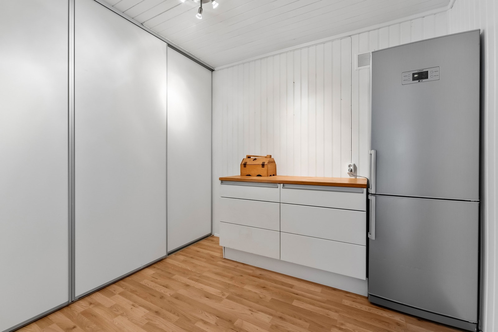 Omkledningsrom med flotte oppbevaringsmuligheter i skyvedørsgarderobe, innredning med benk og skuffeløsning, samt plass til et praktisk ekstra kjøleskap eller fryser Galleribilde