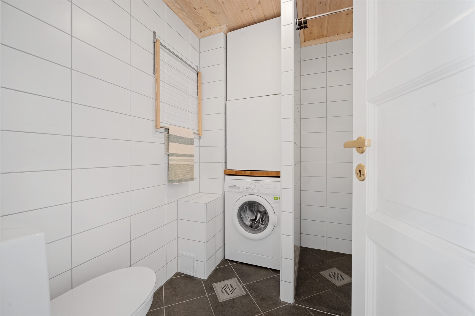 Bad med dusjhjørne, servant med skuffer, høyskap, wc og opplegg vaskemaskin. Galleribilde