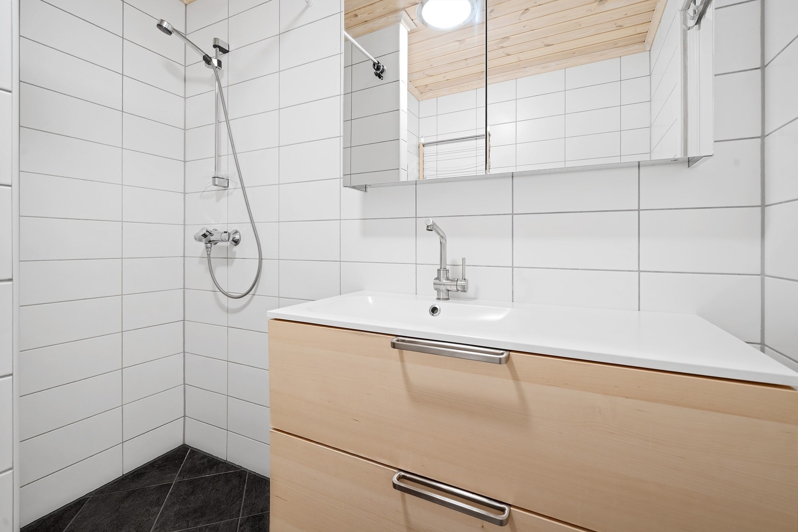 Bad med dusjhjørne, servant med skuffer, høyskap, wc og opplegg vaskemaskin. Galleribilde