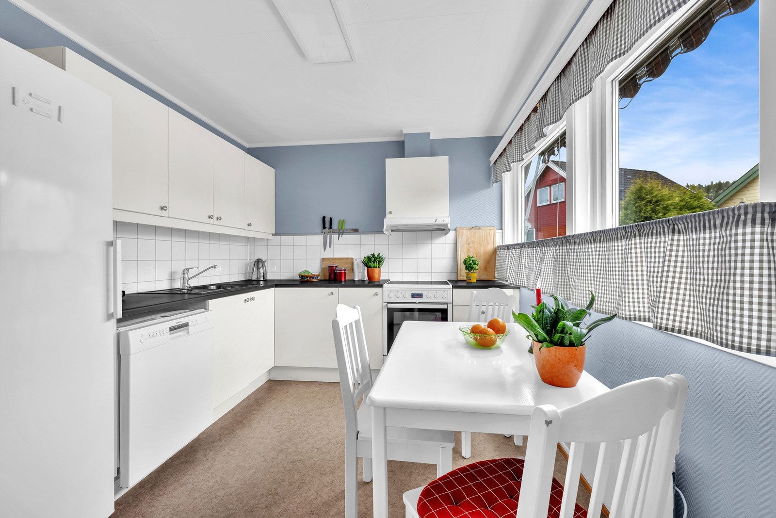Kjøkkenet malt i en lun blåfarge og har god plass til et spisebord under vinduet. Galleribilde