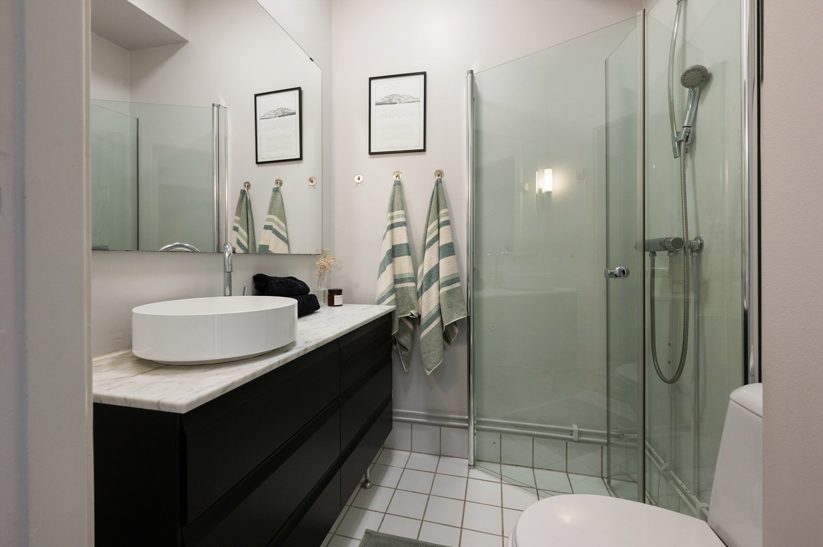 Lyst bad med fliser på gulv, dusjhjørne med innfellbare dusjdører og gulvstående toalett. Galleribilde